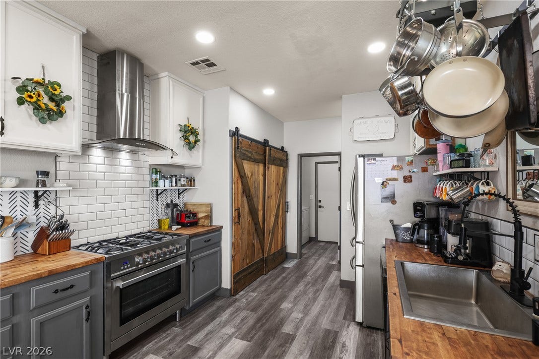 7066 Shimmering Avenue, Henderson, NV 89011 Warm wood countertops and sliding barn door pantry contrast with sleek stainless steel appliances.