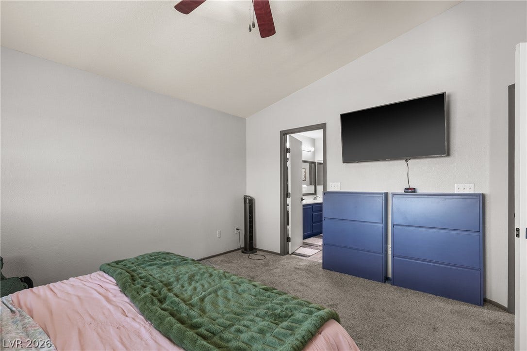 7066 Shimmering Avenue, Henderson, NV 89011 A spacious bedroom features soft wall-to-wall carpeting and an adjoining private bathroom.
