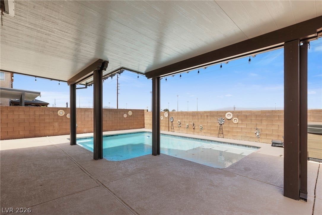 7066 Shimmering Avenue, Henderson, NV 89011 A covered patio overlooks a sparkling in-ground pool enclosed by a privacy wall.