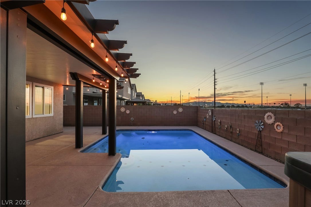 7066 Shimmering Avenue, Henderson, NV 89011 An inviting backyard oasis centers around a sparkling swimming pool framed by a partial pergola.