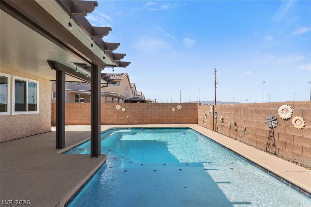 7066 Shimmering Avenue, Henderson, NV 89011 An inviting backyard features a sparkling swimming pool bordered by concrete decking and privacy walls.
