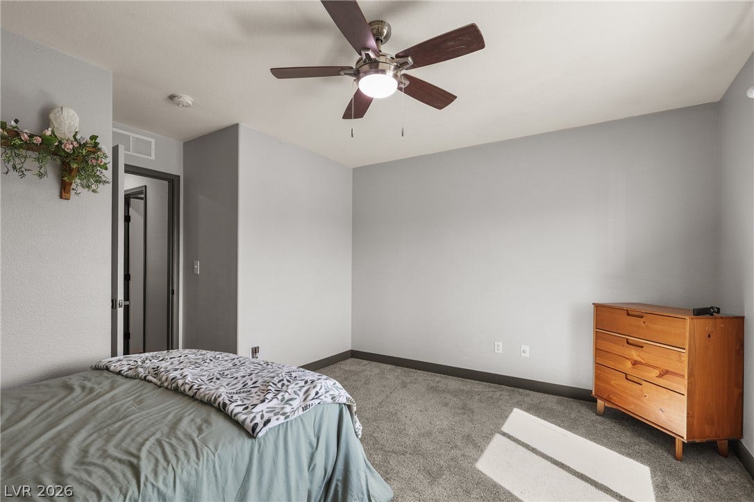 7066 Shimmering Avenue, Henderson, NV 89011 Plush carpeting underfoot anchors this quiet bedroom space, featuring a neutral color palette.