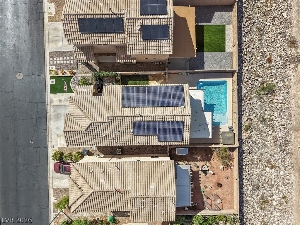 7066 Shimmering Avenue, Henderson, NV 89011 An aerial perspective showcases the tiled rooftops equipped with solar panels and a backyard pool.