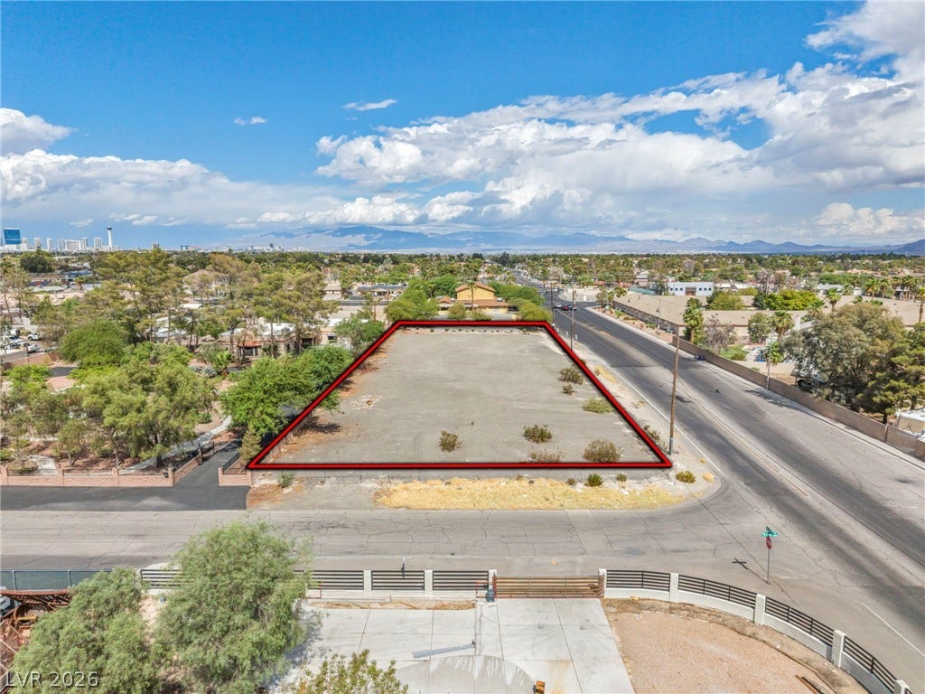 E Quail, Las Vegas, NV 89120 A spacious vacant lot is framed by paved streets and distant mountain silhouettes.