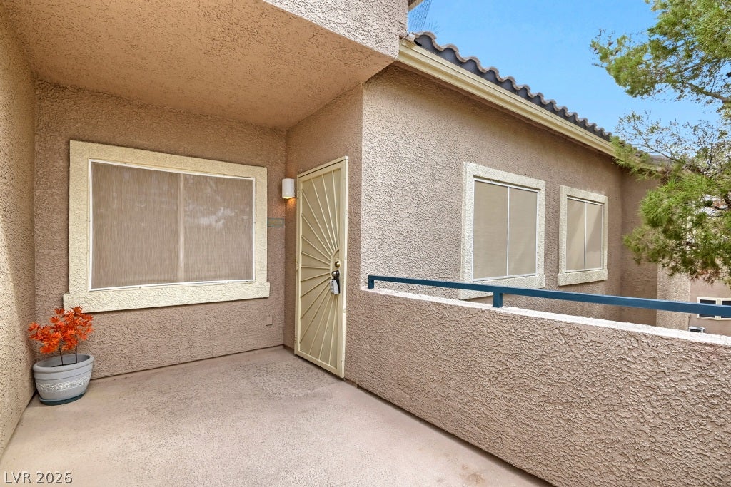 Textured stucco exterior walls surround a concrete balcony walkway leading to a private entrance.