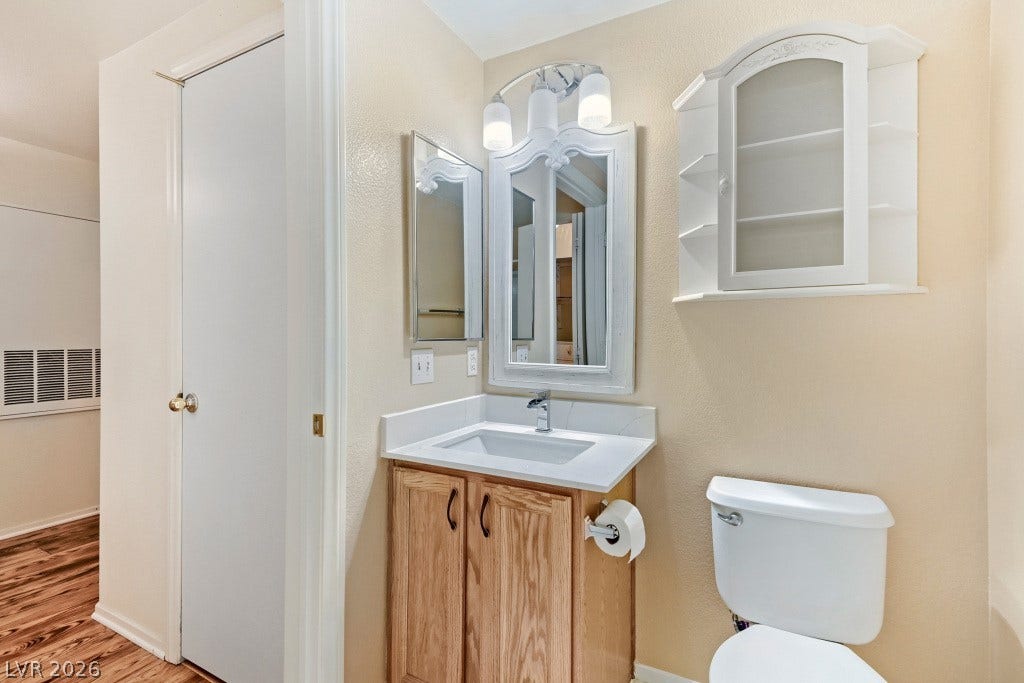 Light neutral walls surround a classic wood vanity topped with solid stone.
