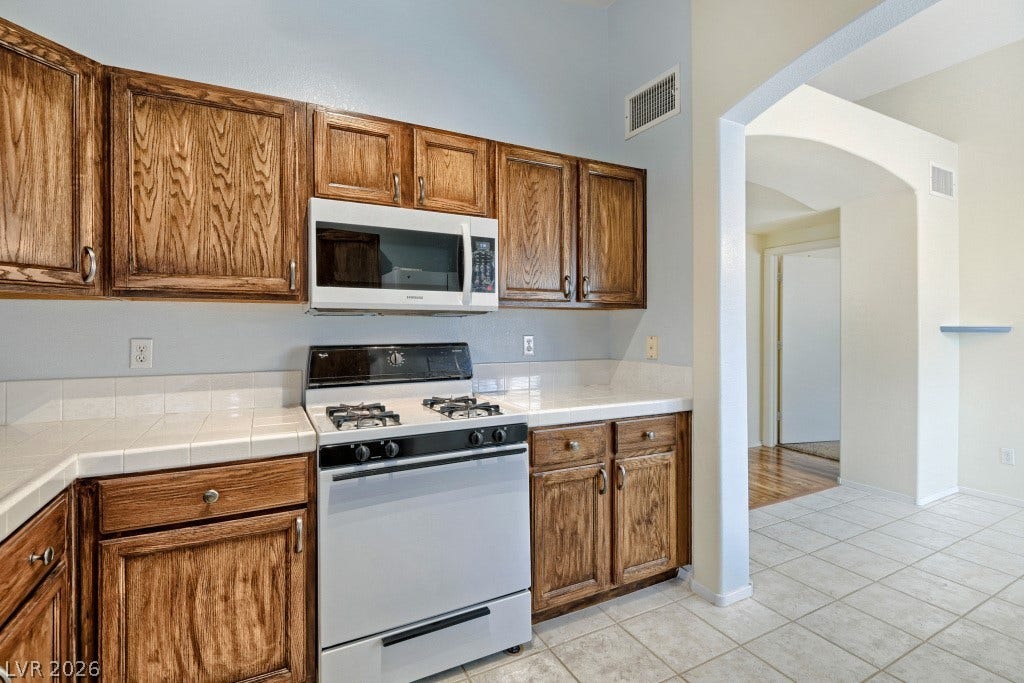 Warm wooden cabinetry and tiled floors frame this functional kitchen workspace.