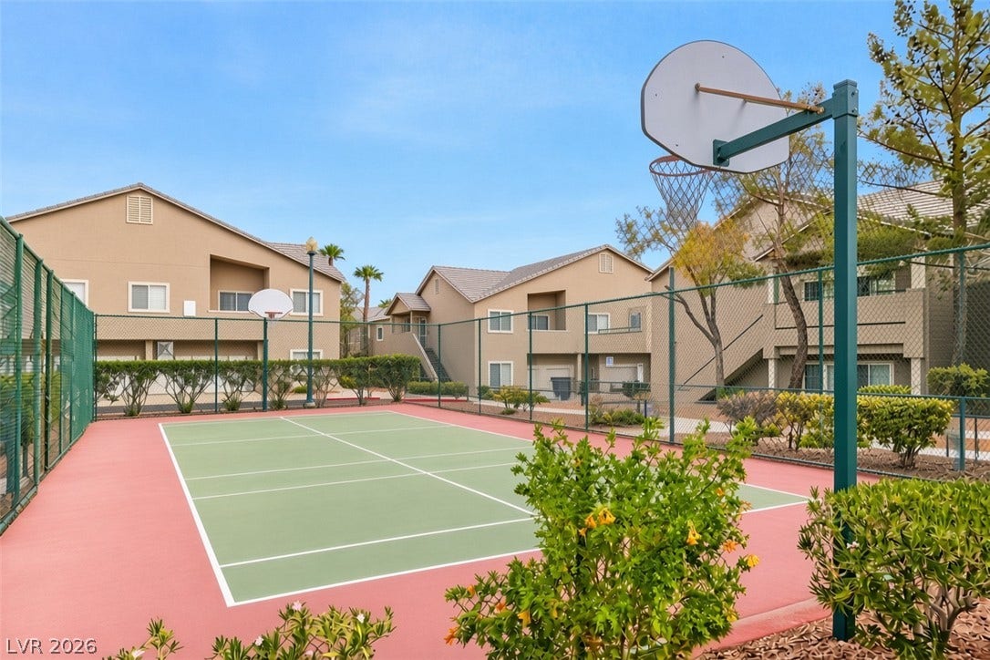 A well-maintained community sports court sits enclosed by fencing near residential buildings.
