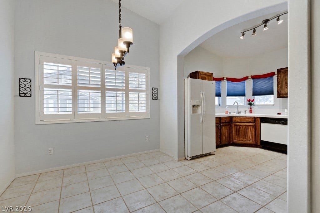 An arched doorway connects the tiled dining area to a well-lit kitchen space.