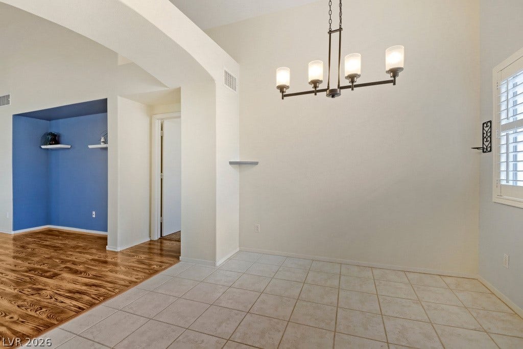 Soaring ceilings and clean tile flooring define this airy open-concept dining space.