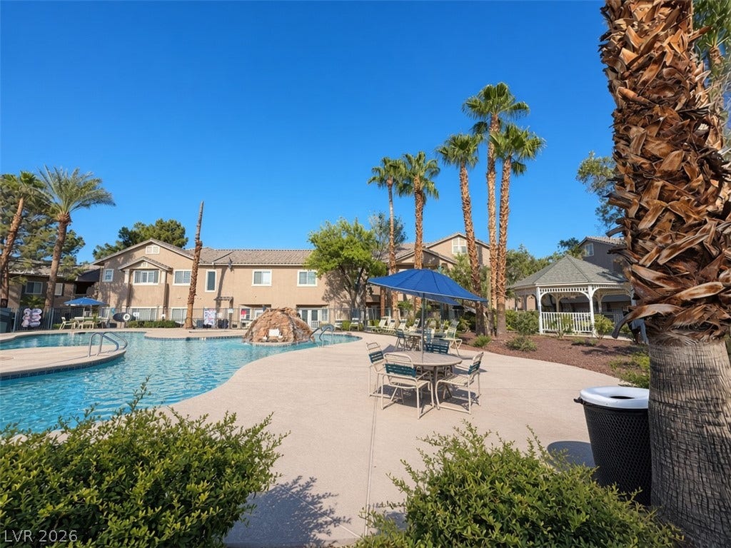 Mature palm trees frame a expansive community pool area complete with a classic gazebo.