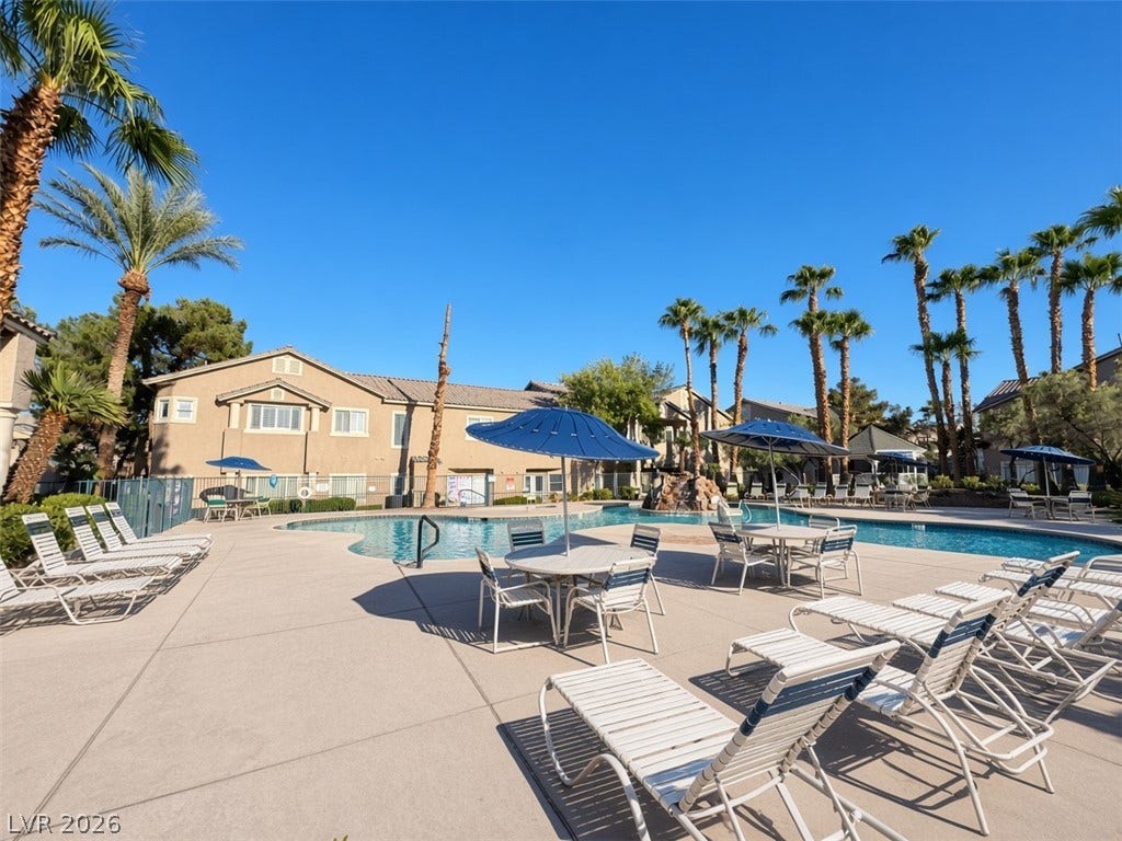 Palm trees surround a spacious concrete sundeck and sparkling community swimming pool.