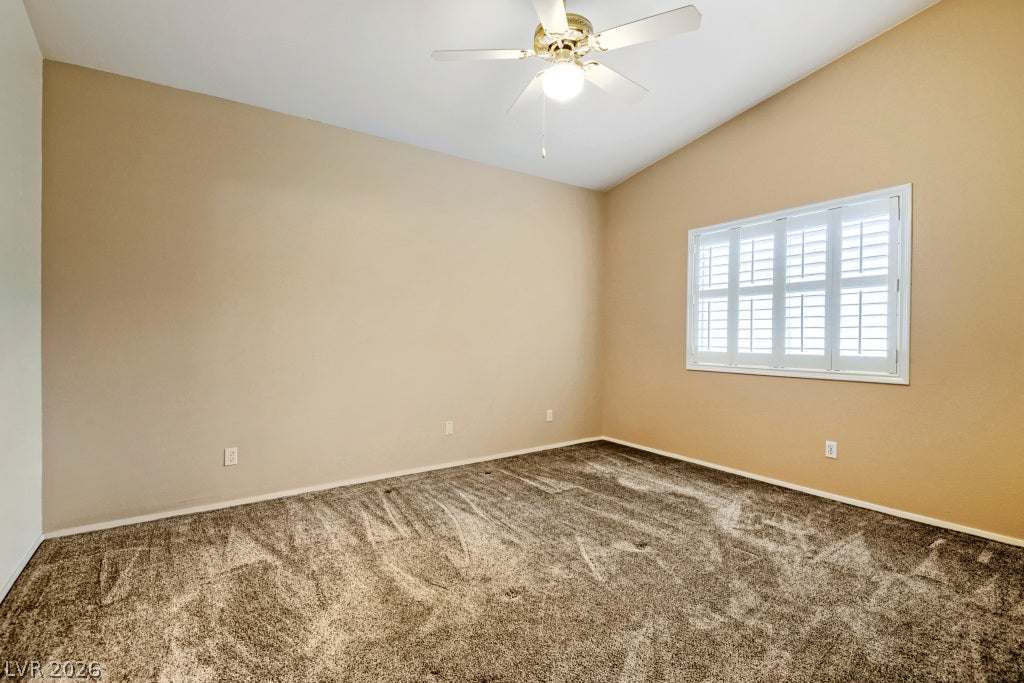 Plush carpeting and classic plantation shutters define this serene, vaulted bedroom.