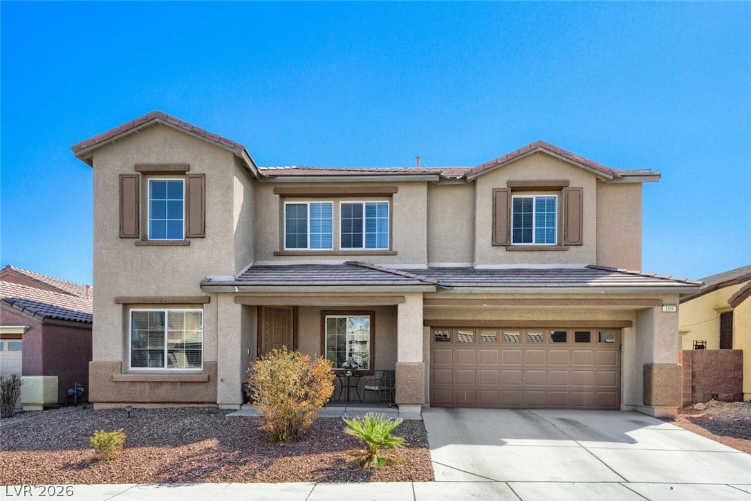 109 Spur Ranch Avenue, North Las Vegas, NV 89032 An inviting two-story stucco exterior displays decorative window shutters, a front porch, and tile roofing.