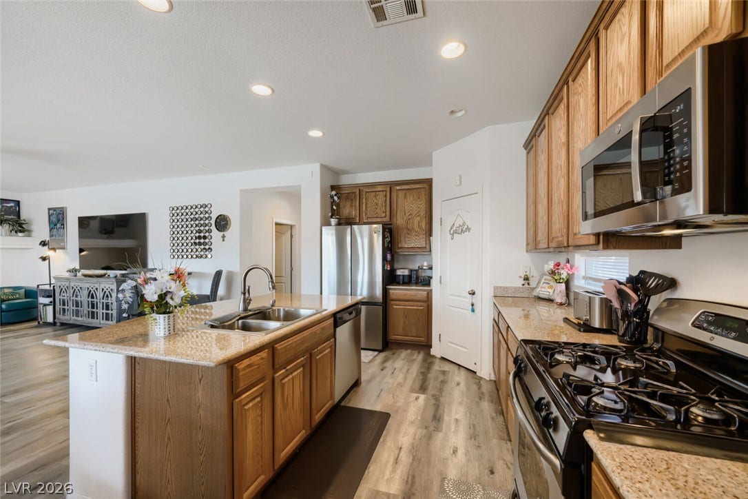 109 Spur Ranch Avenue, North Las Vegas, NV 89032 Warm wood cabinetry and granite countertops anchor this open-concept kitchen space.