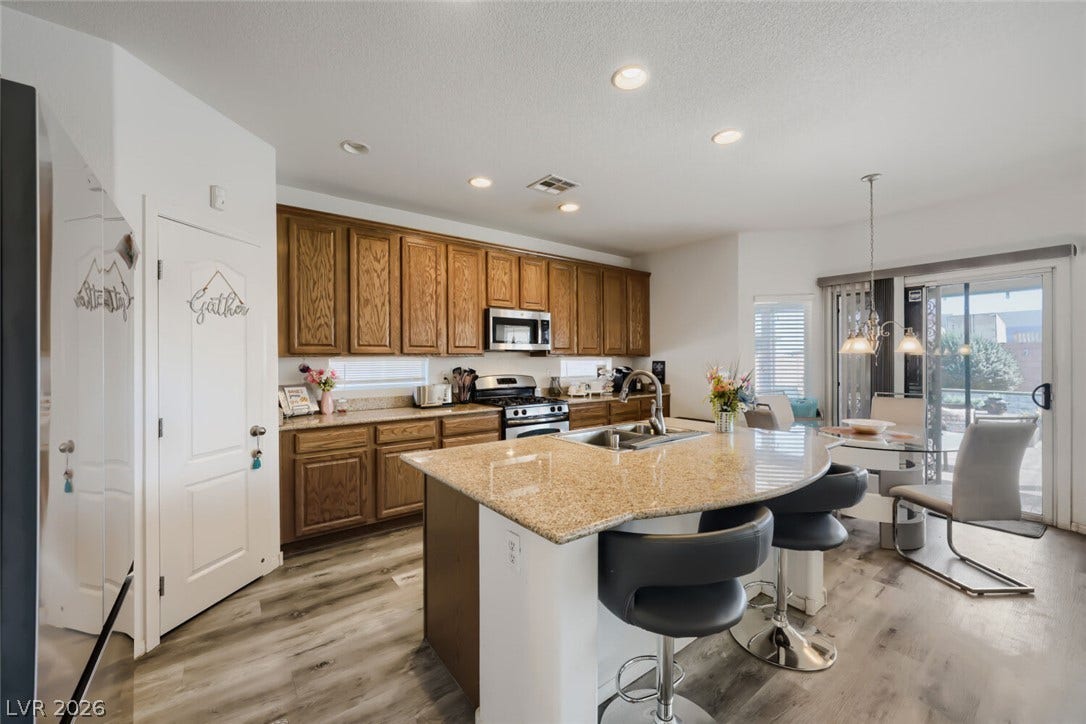 109 Spur Ranch Avenue, North Las Vegas, NV 89032 Gleaming stone countertops and warm wood cabinetry anchor this light-filled culinary workspace.