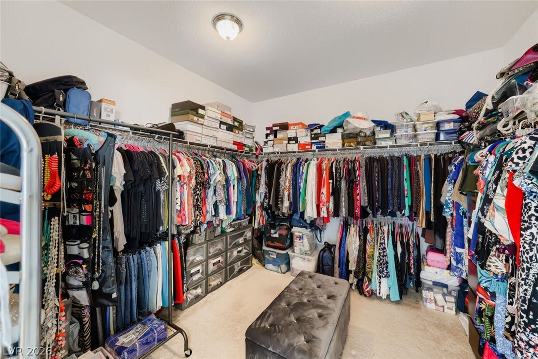 109 Spur Ranch Avenue, North Las Vegas, NV 89032 A spacious walk-in closet includes carpet flooring and extensive clothing racks with built-in storage shelves.