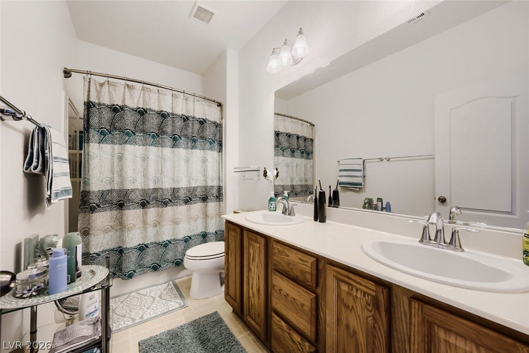 109 Spur Ranch Avenue, North Las Vegas, NV 89032 Double sinks and wood cabinetry define this functional bathroom space.