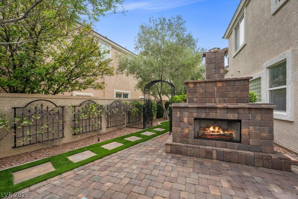 9521 Queen Charlotte Drive, Las Vegas, NV 89145 An inviting stone fireplace anchors the paved courtyard, framed by manicured garden borders.