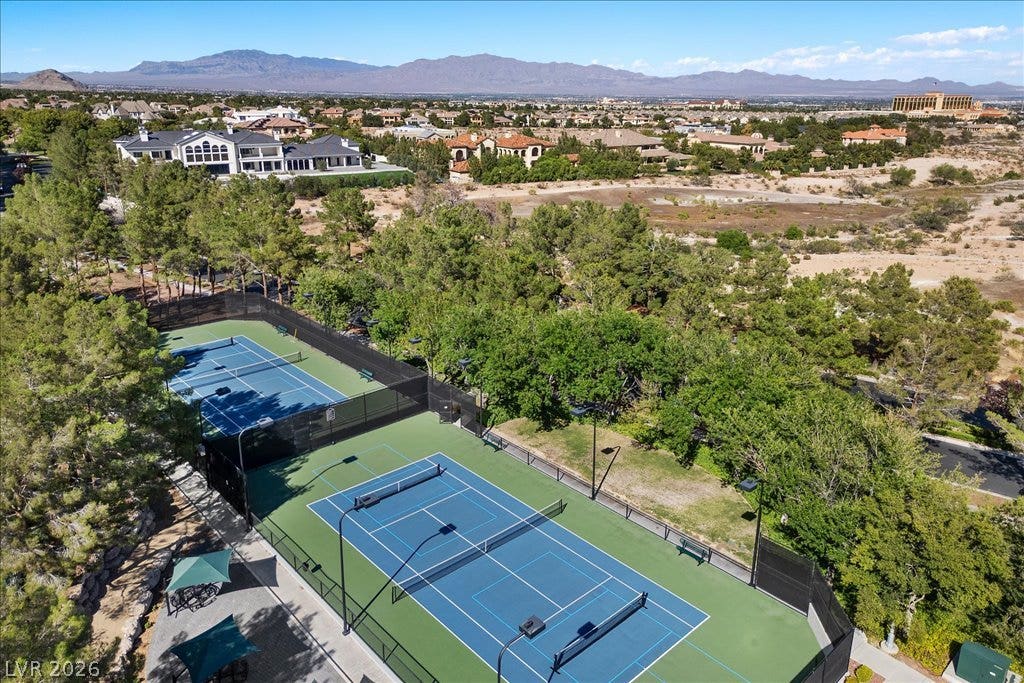 9521 Queen Charlotte Drive, Las Vegas, NV 89145 Double tennis courts sit surrounded by mature trees against a majestic mountain backdrop.
