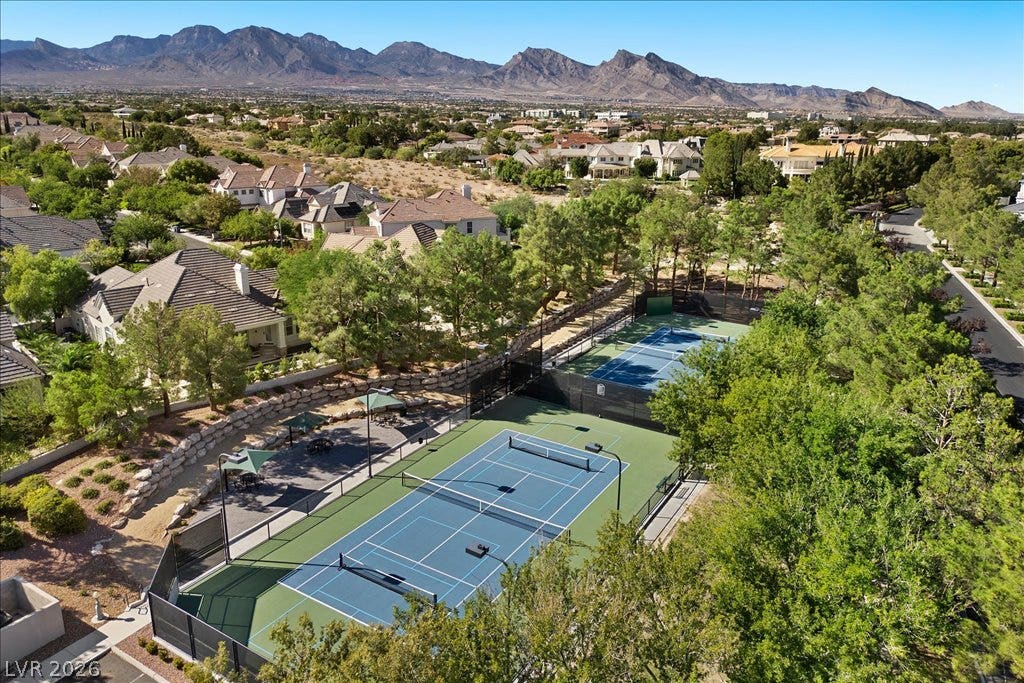 9521 Queen Charlotte Drive, Las Vegas, NV 89145 Fenced tennis courts rest against a backdrop of mature trees and distant mountain peaks.