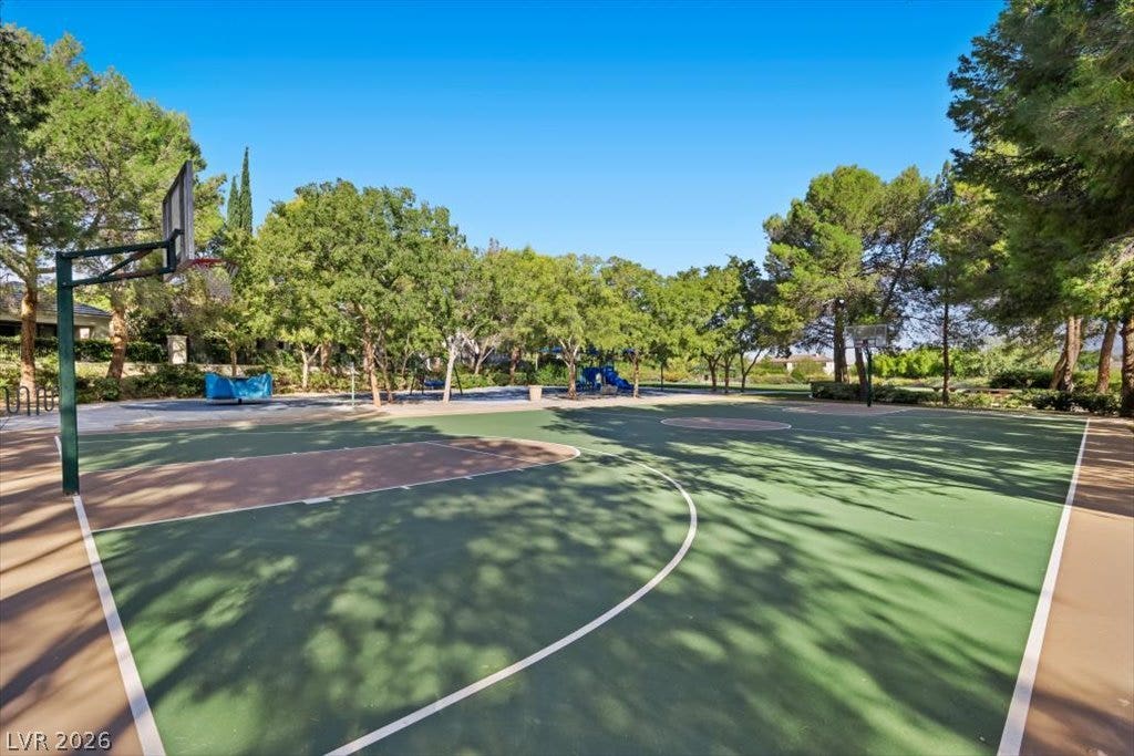 9521 Queen Charlotte Drive, Las Vegas, NV 89145 Mature trees frame a spacious outdoor basketball court set beneath clear blue skies.