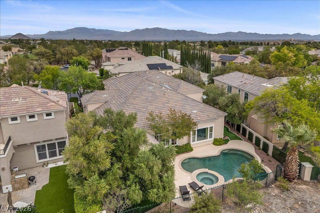 9521 Queen Charlotte Drive, Las Vegas, NV 89145 A sparkling backyard swimming pool is nestled alongside a tile-roofed home with distant mountain views.