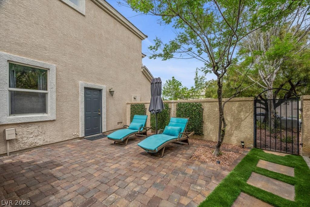 9521 Queen Charlotte Drive, Las Vegas, NV 89145 An inviting paved patio area is bordered by stucco walls and a classic iron gate.