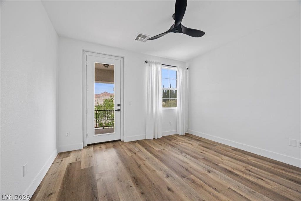 9521 Queen Charlotte Drive, Las Vegas, NV 89145 Rich wood-inspired flooring and a glass patio door define this versatile modern bedroom.