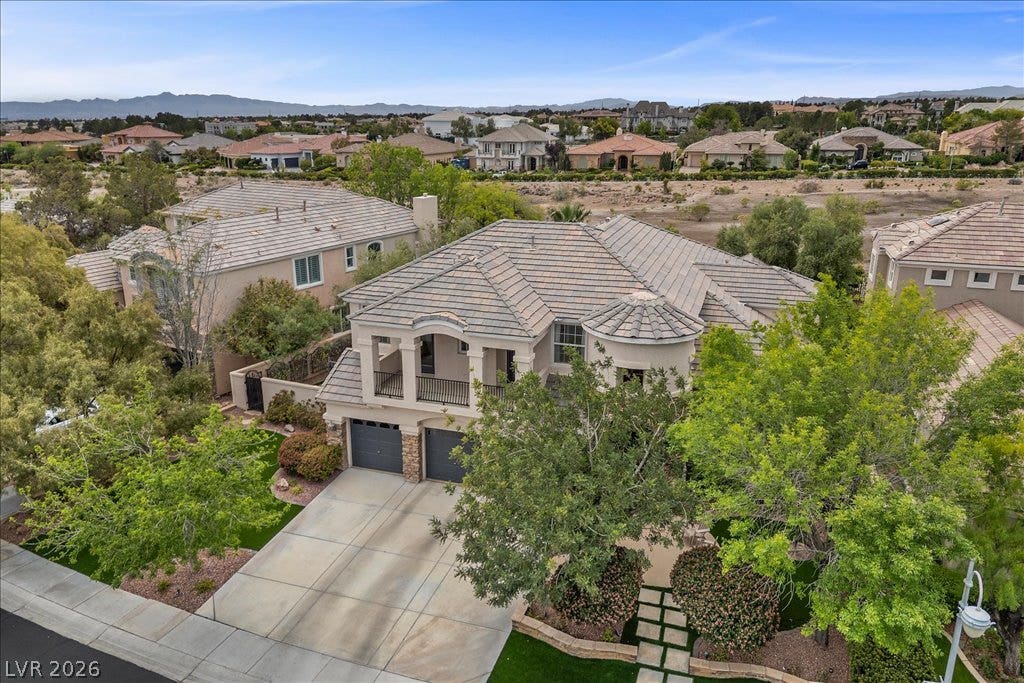 9521 Queen Charlotte Drive, Las Vegas, NV 89145 An aerial perspective showcases the tiled rooflines and paved driveway of this multi-level suburban home.