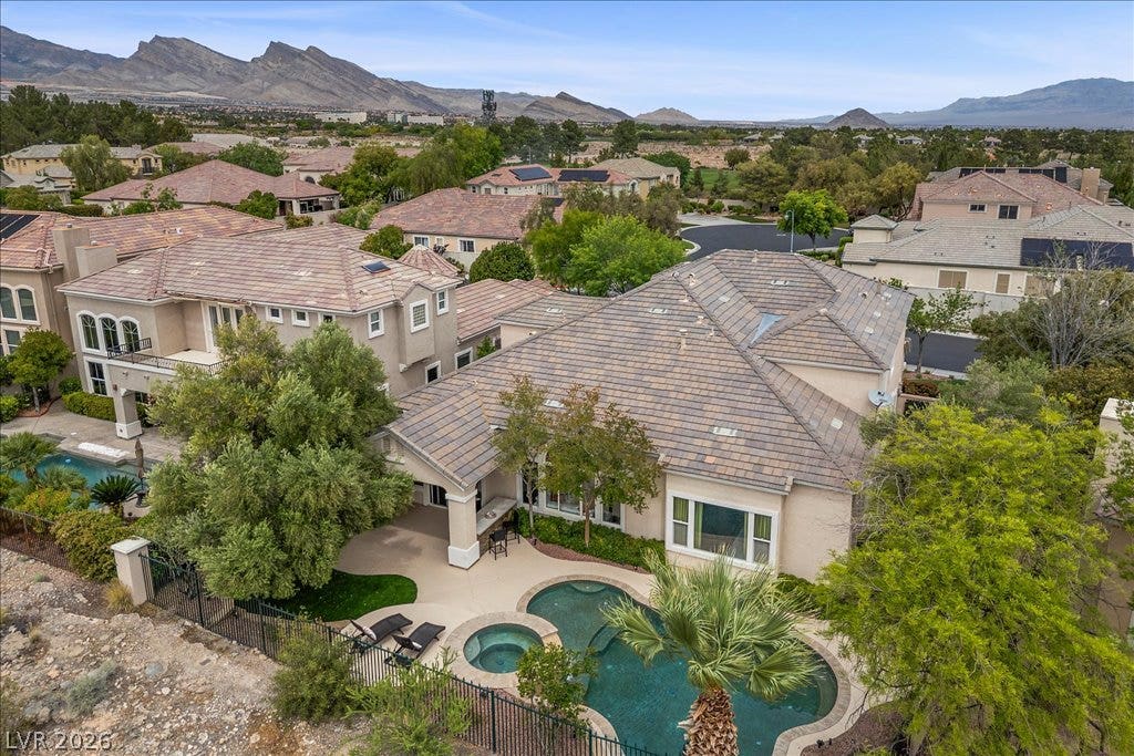 9521 Queen Charlotte Drive, Las Vegas, NV 89145 A private backyard oasis features a swimming pool with spa against a majestic mountain backdrop.