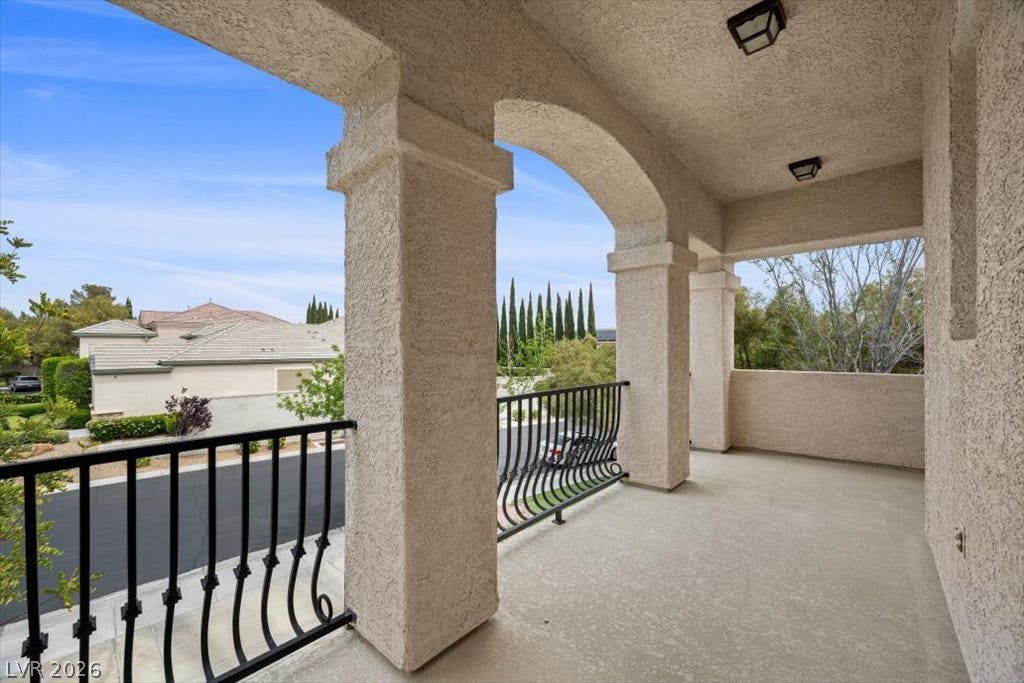 9521 Queen Charlotte Drive, Las Vegas, NV 89145 Stately stucco arches and wrought iron railings frame peaceful neighborhood views from the elevated balcony.