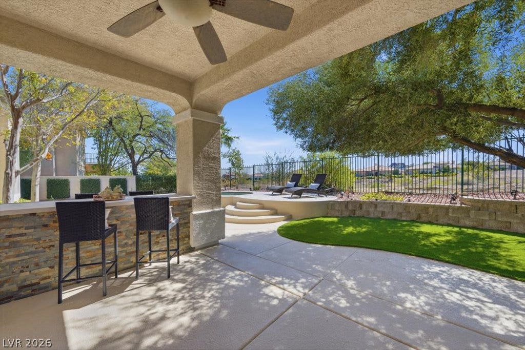 9521 Queen Charlotte Drive, Las Vegas, NV 89145 An inviting covered patio steps down to a sunny backyard with lush lawn and mature trees.