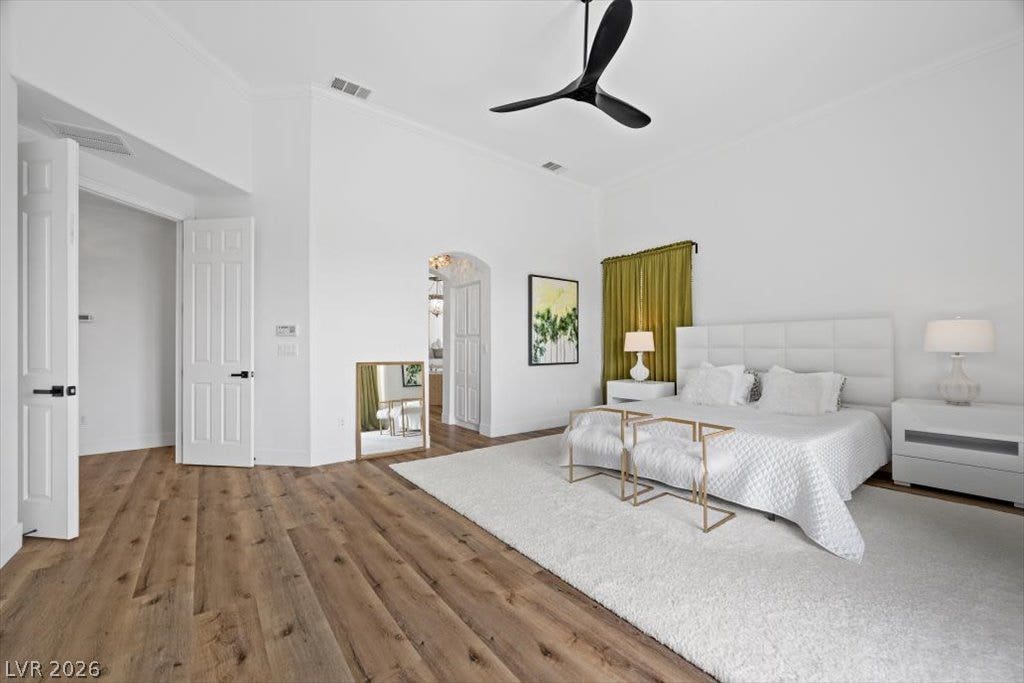 9521 Queen Charlotte Drive, Las Vegas, NV 89145 Rich hardwood flooring complements the soaring high ceilings and arched doorway of this primary suite.