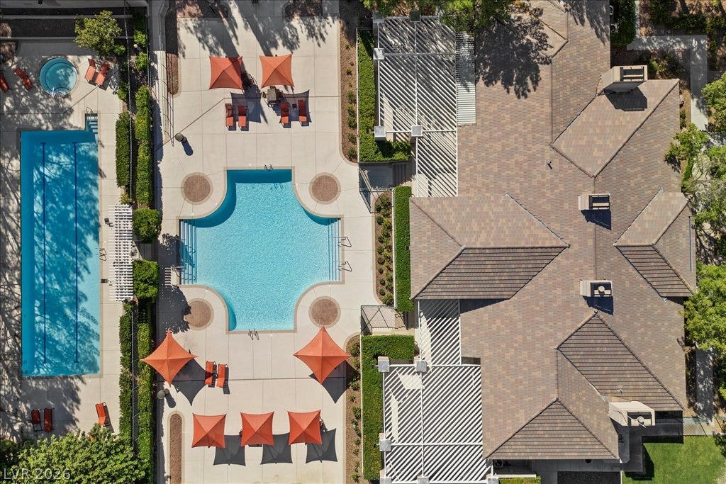 9521 Queen Charlotte Drive, Las Vegas, NV 89145 An aerial perspective reveals meticulously planned swimming facilities and structured concrete patios adjacent to shingled roofs.