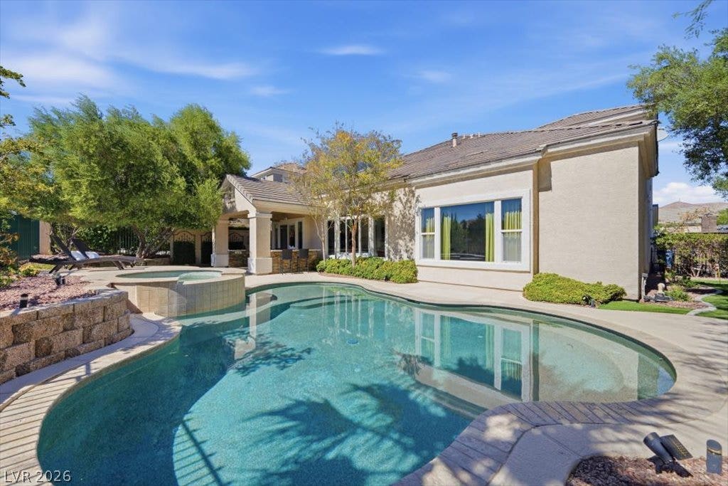 9521 Queen Charlotte Drive, Las Vegas, NV 89145 An inviting backyard oasis features a curved swimming pool and matching spa alongside the home.