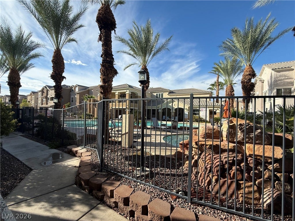 8777 W Maule Avenue, #1094, Las Vegas, NV 89148 Mature palm trees frame a gated community pool area under a bright blue sky.