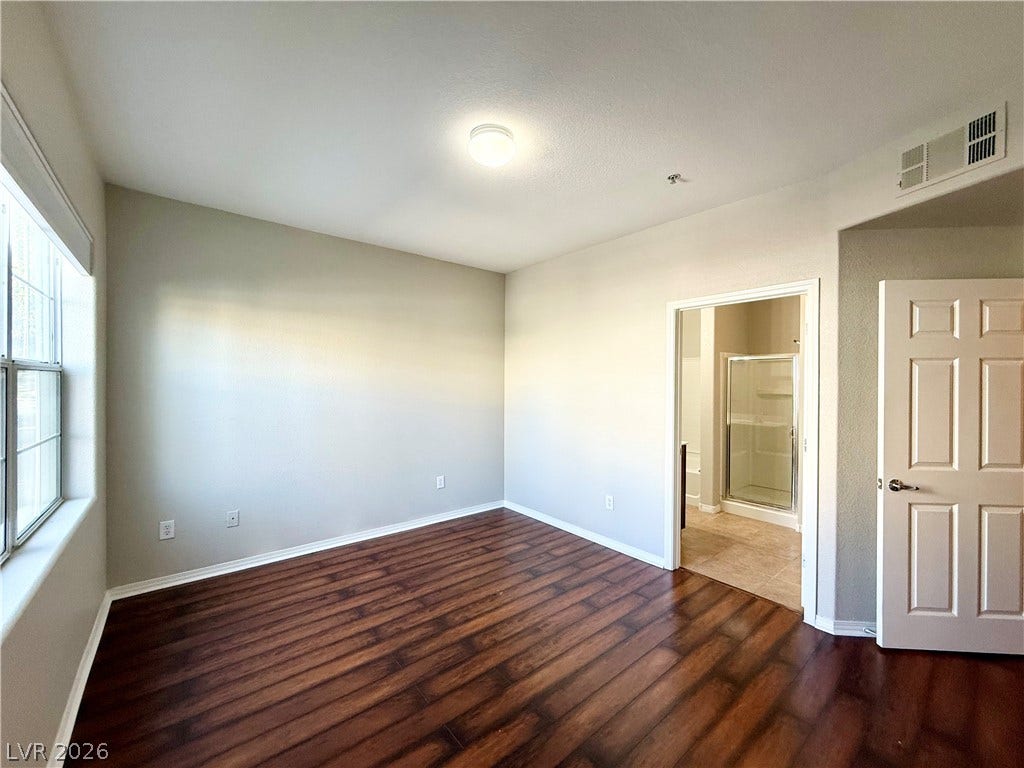 8777 W Maule Avenue, #1094, Las Vegas, NV 89148 Gleaming wood-look floors pair with neutral walls in this bedroom featuring an attached bathroom.