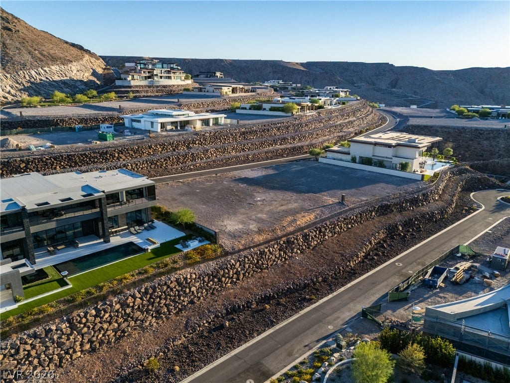 7 Sunset Strip, Henderson, NV 89012 An aerial view showcases terraced lots nestled against rugged desert hillsides with modern residences.