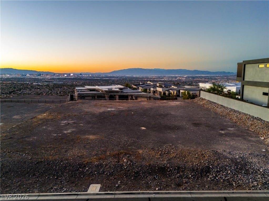 7 Sunset Strip, Henderson, NV 89012 An elevated vacant building lot showcases sweeping valley, city light, and mountain views at sunset.