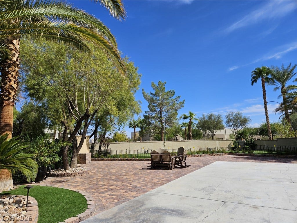8175 Arville Street, #33, Las Vegas, NV 89139 Mature palms frame a vast paver patio alongside a sprawling concrete recreation surface.