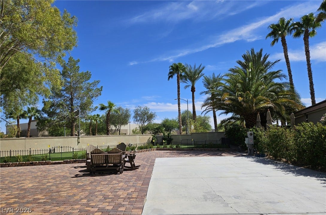 8175 Arville Street, #33, Las Vegas, NV 89139 Towering palm trees frame a spacious paved patio under clear desert skies.