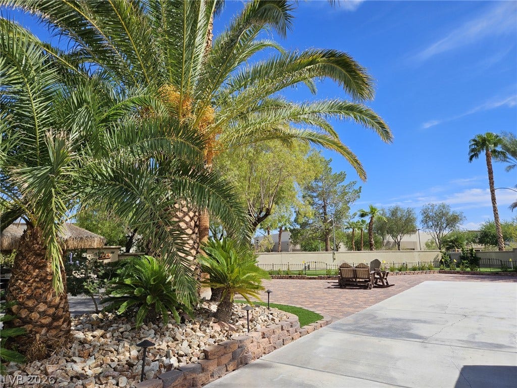 8175 Arville Street, #33, Las Vegas, NV 89139 Lush palm trees frame an expansive paved patio under clear blue desert skies.