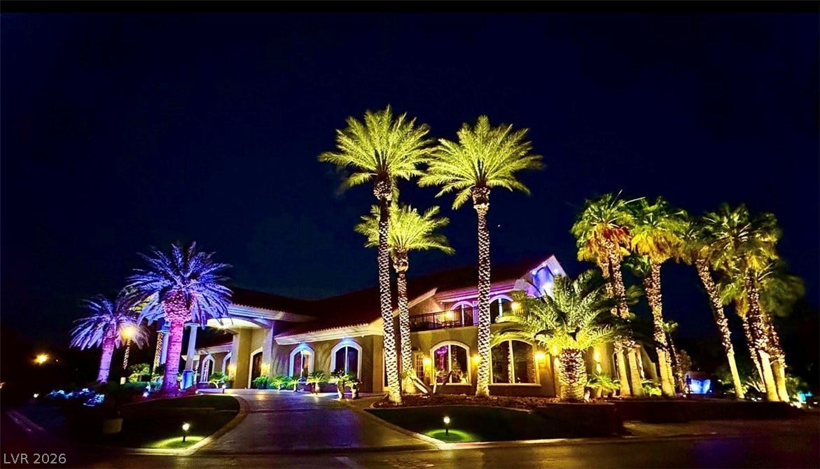 8175 Arville Street, #33, Las Vegas, NV 89139 Dramatic exterior illumination showcases the grand entrance and manicured palm trees at night.