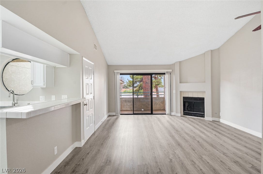 830 N Sloan Lane, #202, Las Vegas, NV 89110 Vaulted ceilings and wood-style flooring enhance this open living area featuring a fireplace.
