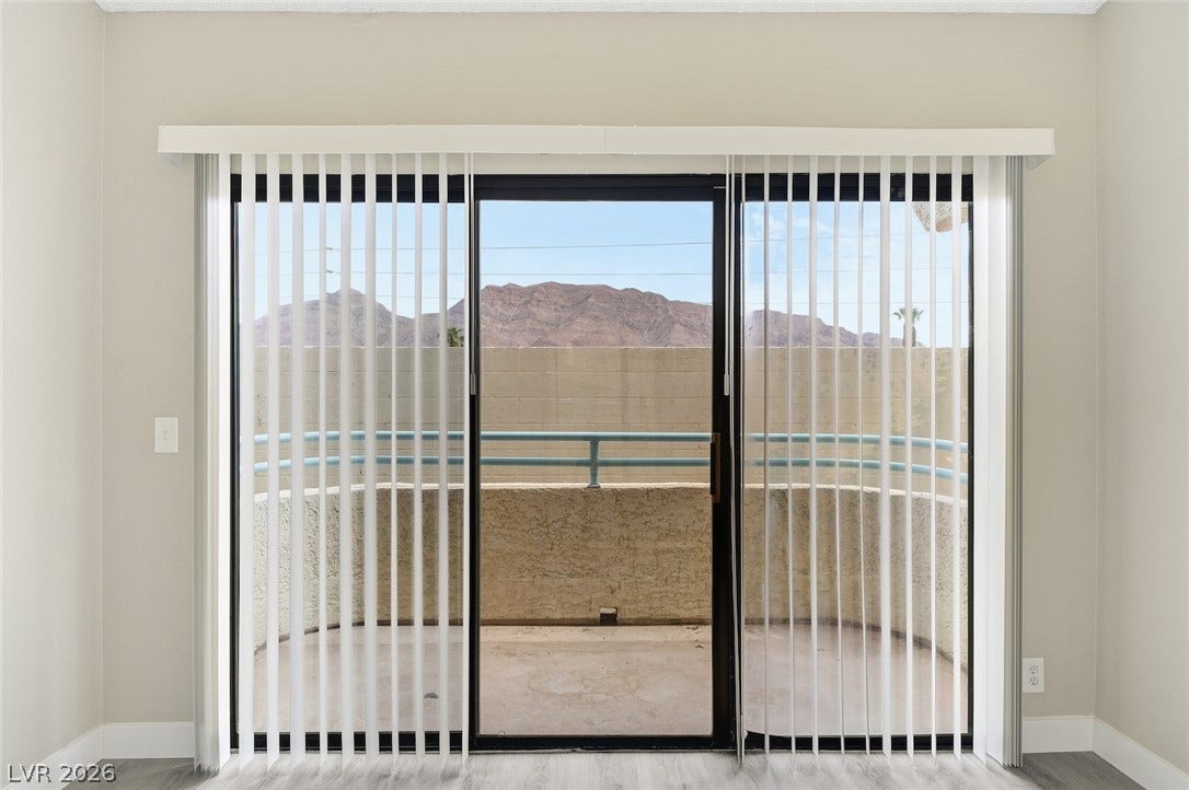 830 N Sloan Lane, #202, Las Vegas, NV 89110 Sliding glass doors open directly to a private balcony showcasing distant mountain views.