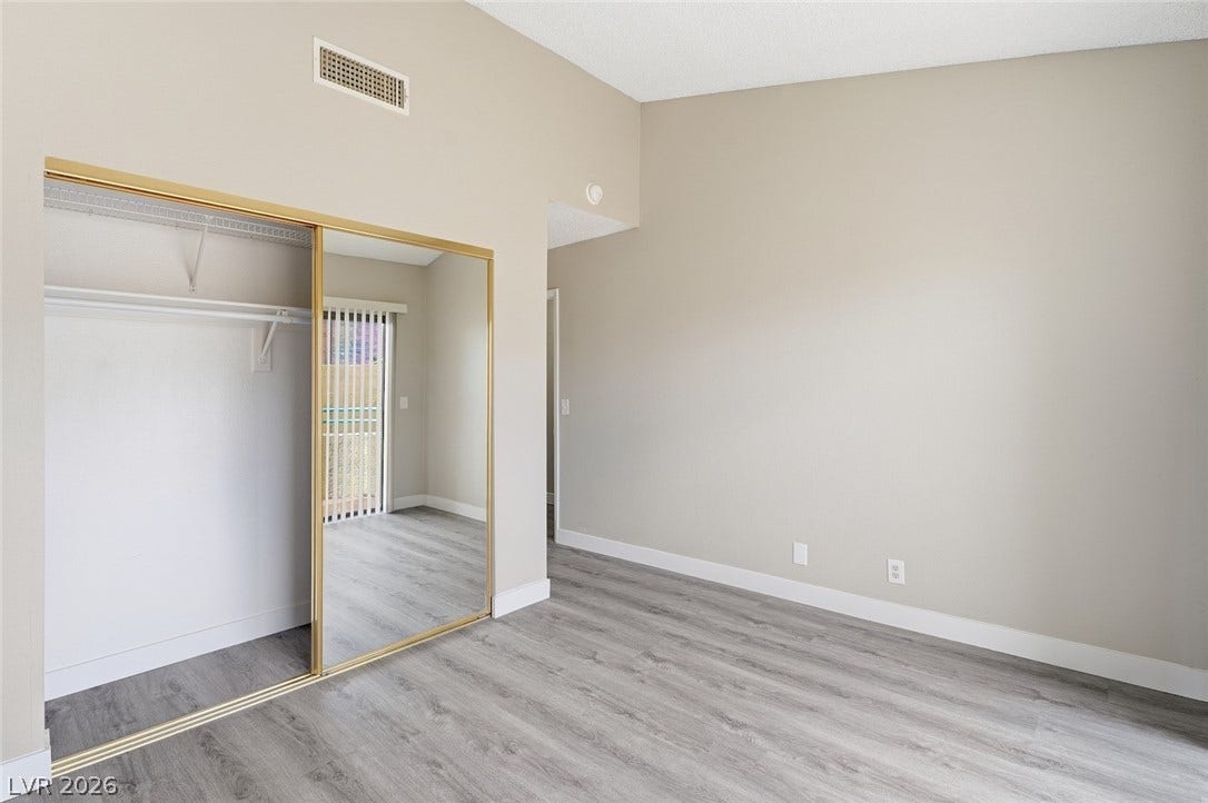 830 N Sloan Lane, #202, Las Vegas, NV 89110 A spacious bedroom features neutral walls, high ceilings, and sliding mirrored closet doors.