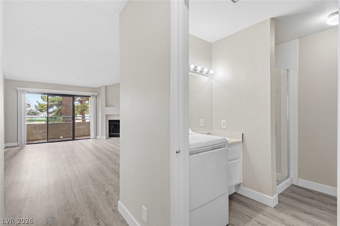 830 N Sloan Lane, #202, Las Vegas, NV 89110 Smooth wood-look flooring connects the utility space and living room highlighted by sliding glass doors.