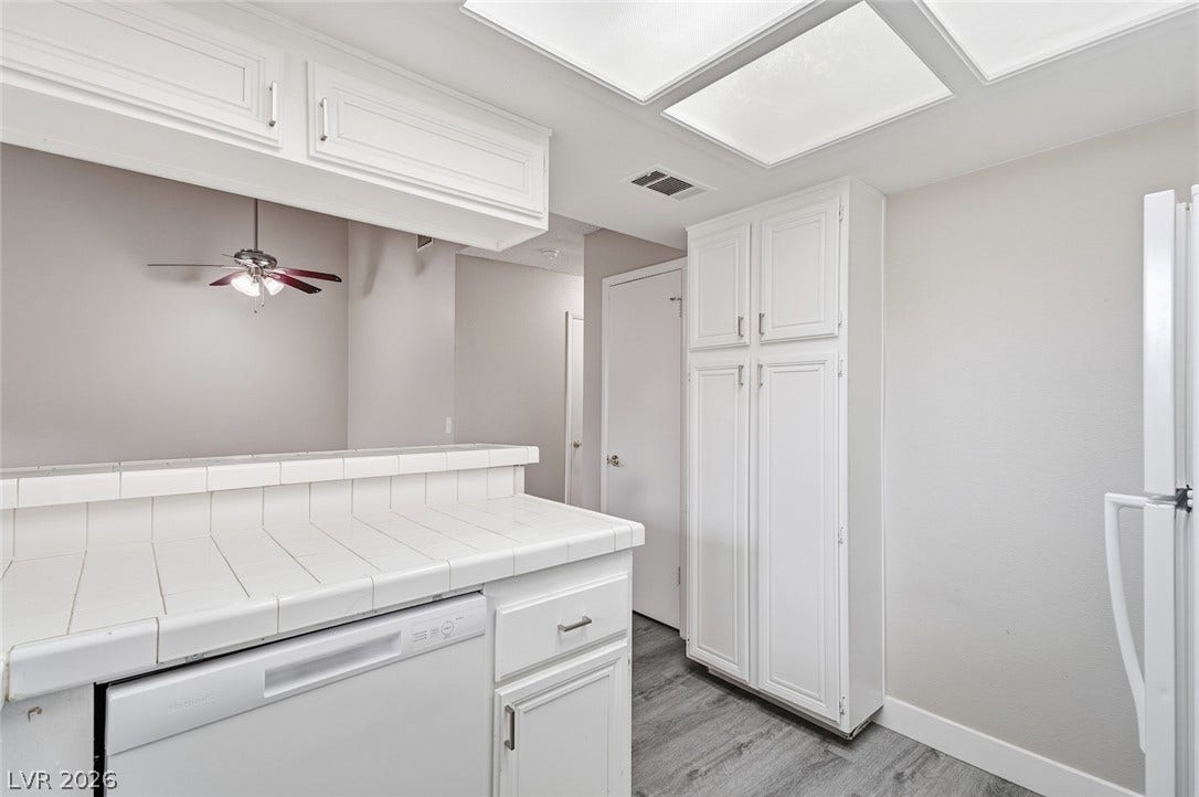 830 N Sloan Lane, #202, Las Vegas, NV 89110 Crisp white cabinetry paired with durable tile countertops anchors this functional culinary space.
