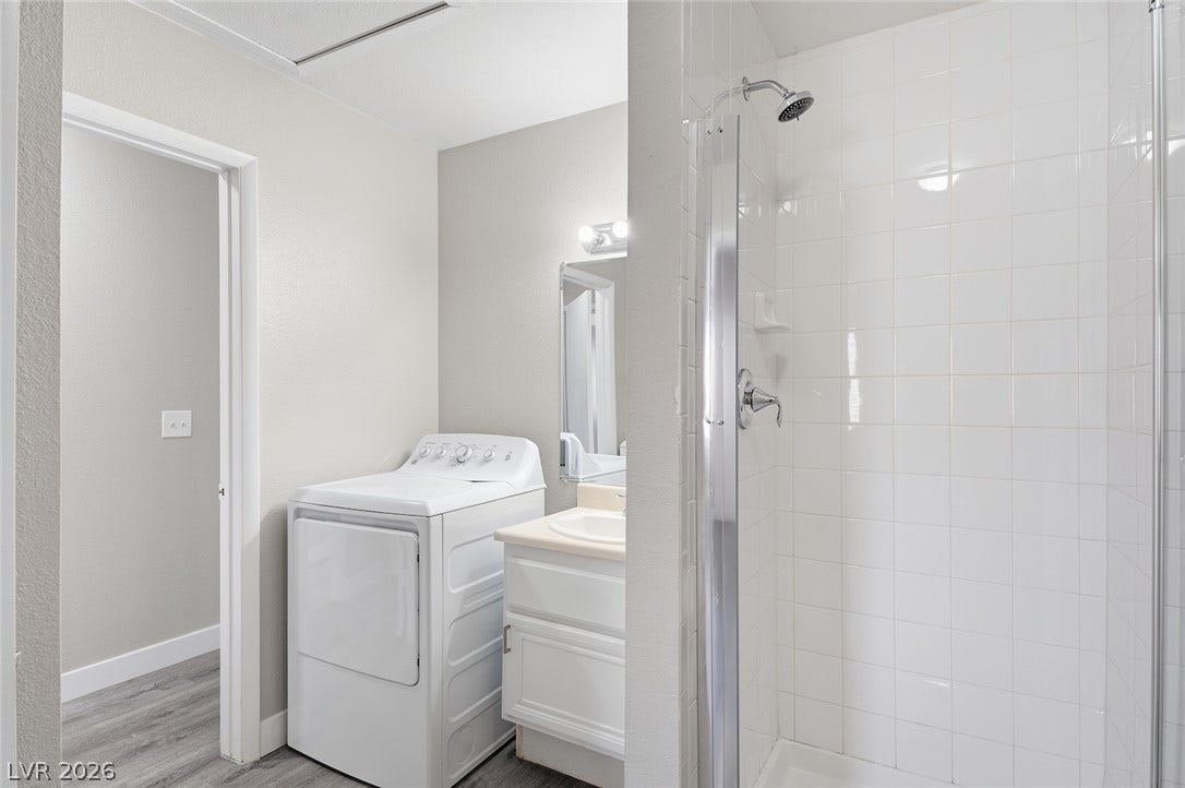 830 N Sloan Lane, #202, Las Vegas, NV 89110 A classic walk-in shower stands adjacent to a functional vanity and laundry setup.